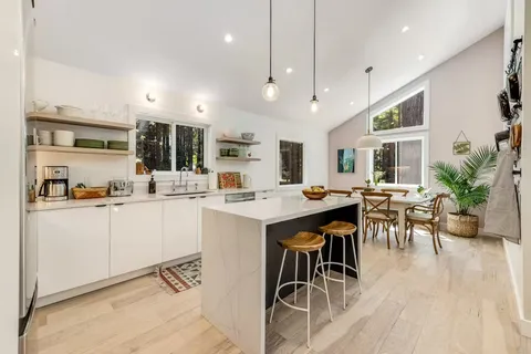 a kitchen with stainless steel appliances kitchen island granite countertop a table chairs in it and white cabinets