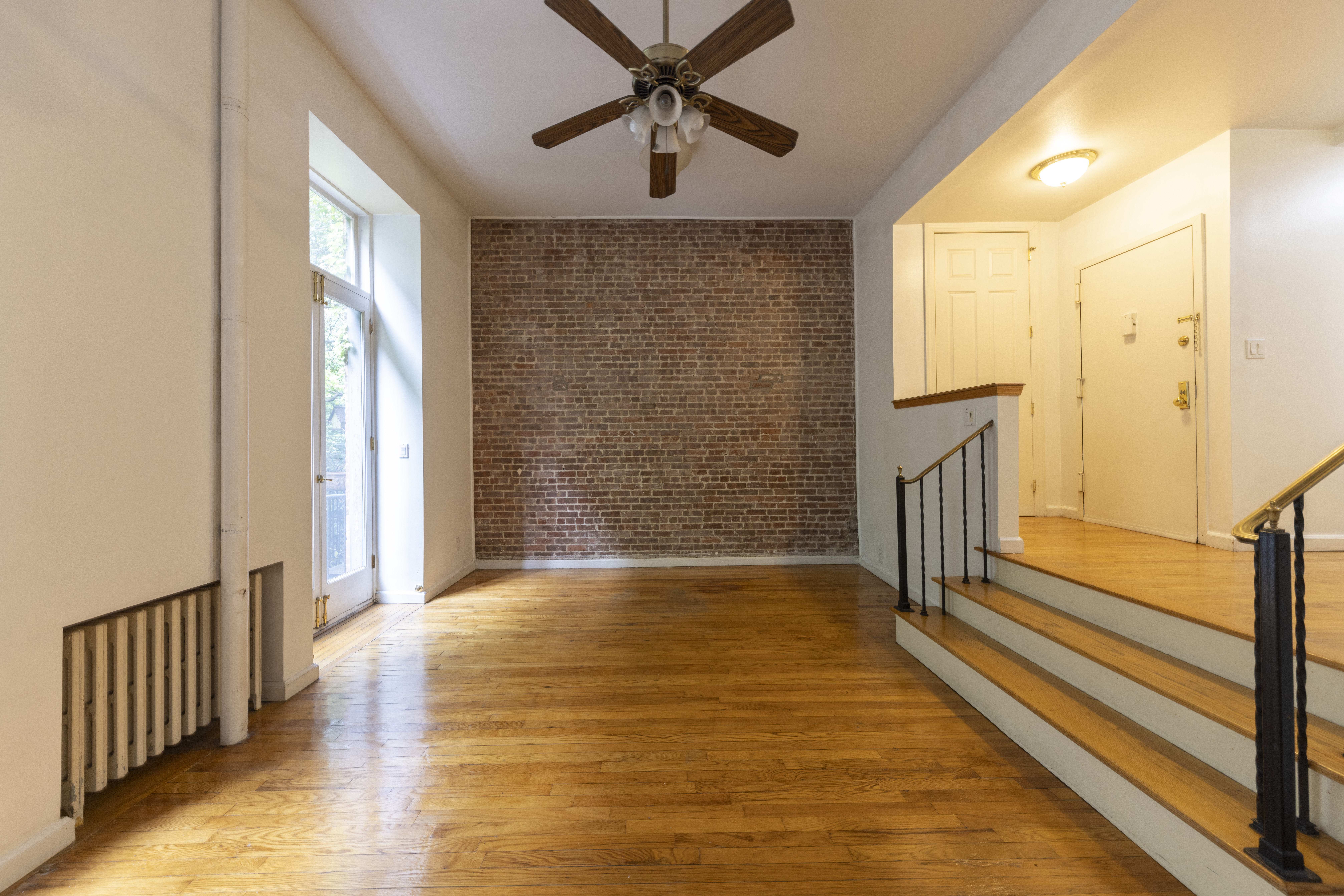 1384 Lexington Avenue, Unit 2 Manhattan, NY 10128 - Photo 7 of 11 a view of a livingroom with wooden floor and a ceiling fan