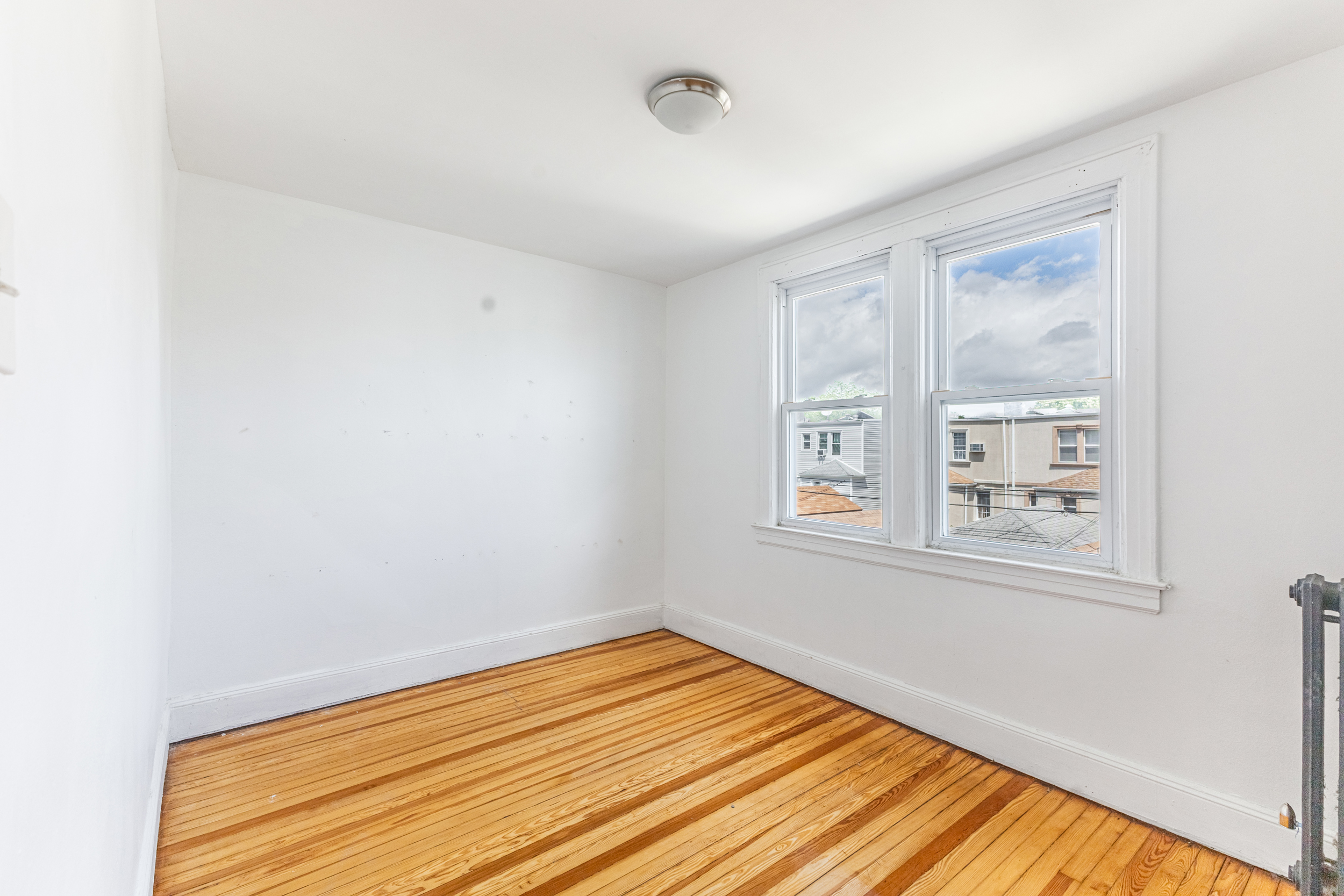 69-29 67th Place Queens, NY 11385 - Photo 14 of 24 a view of an empty room with wooden floor and a window