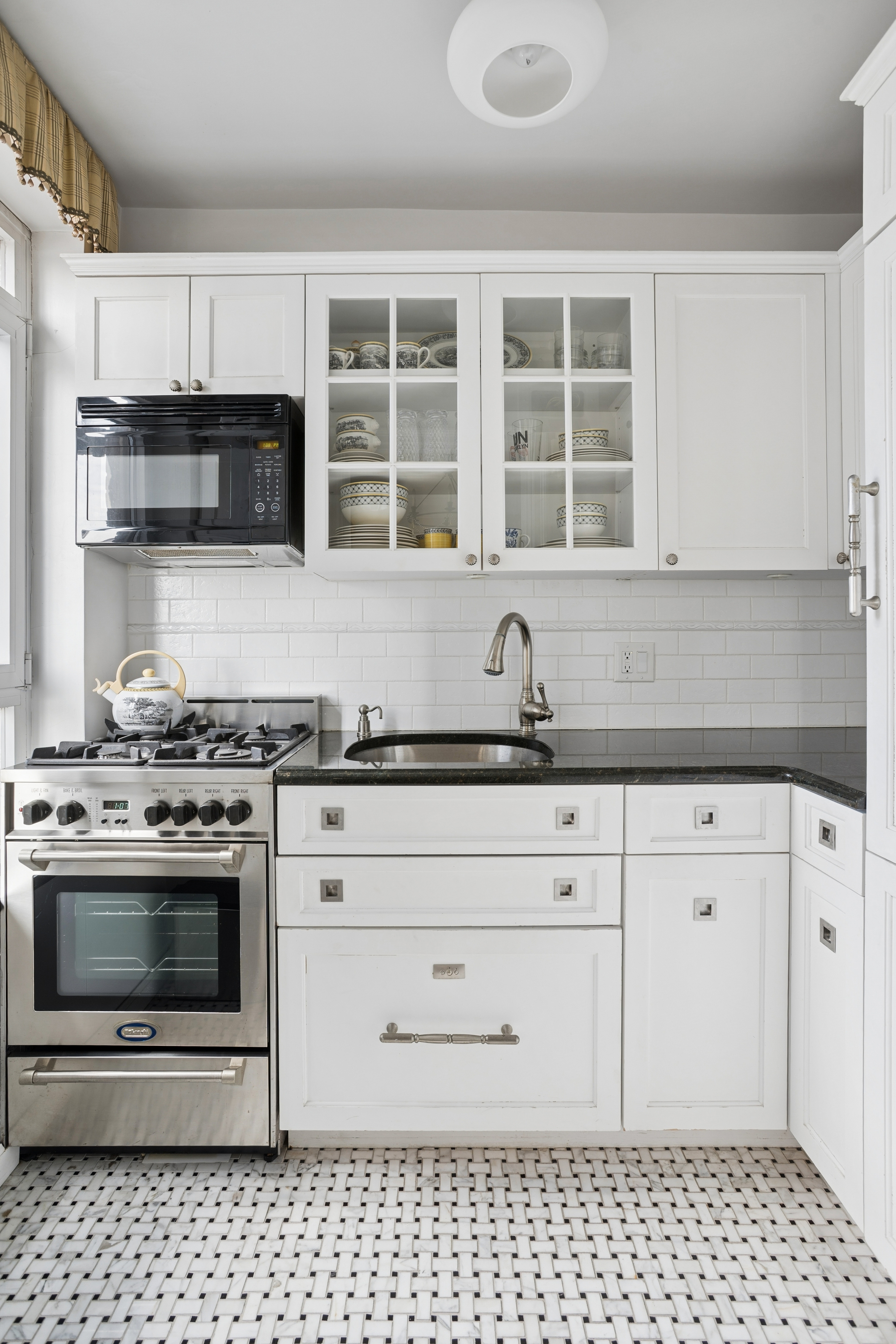 2 Beekman Place, Unit 12D Manhattan, NY 10022 - Photo 2 of 8 a kitchen with white cabinets and appliances
