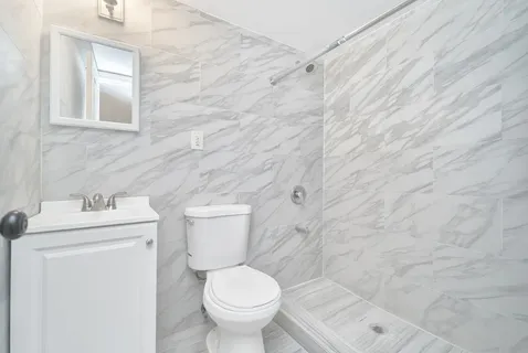 a white toilet sitting next to a white sink and vanity