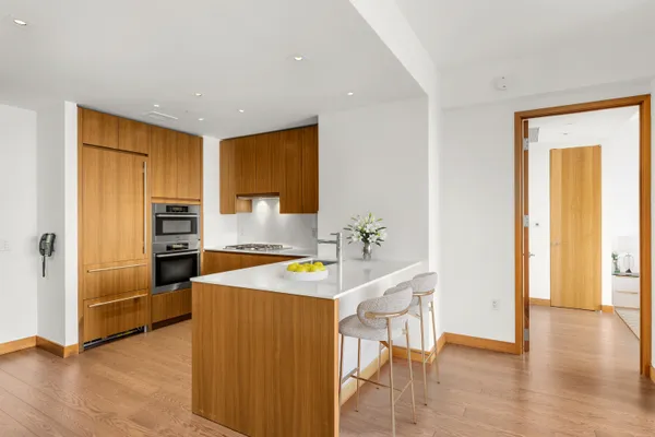 a kitchen with stainless steel appliances granite countertop a refrigerator a stove and a sink with wooden floor