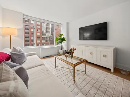 a living room with furniture a flat screen tv and a floor to ceiling window