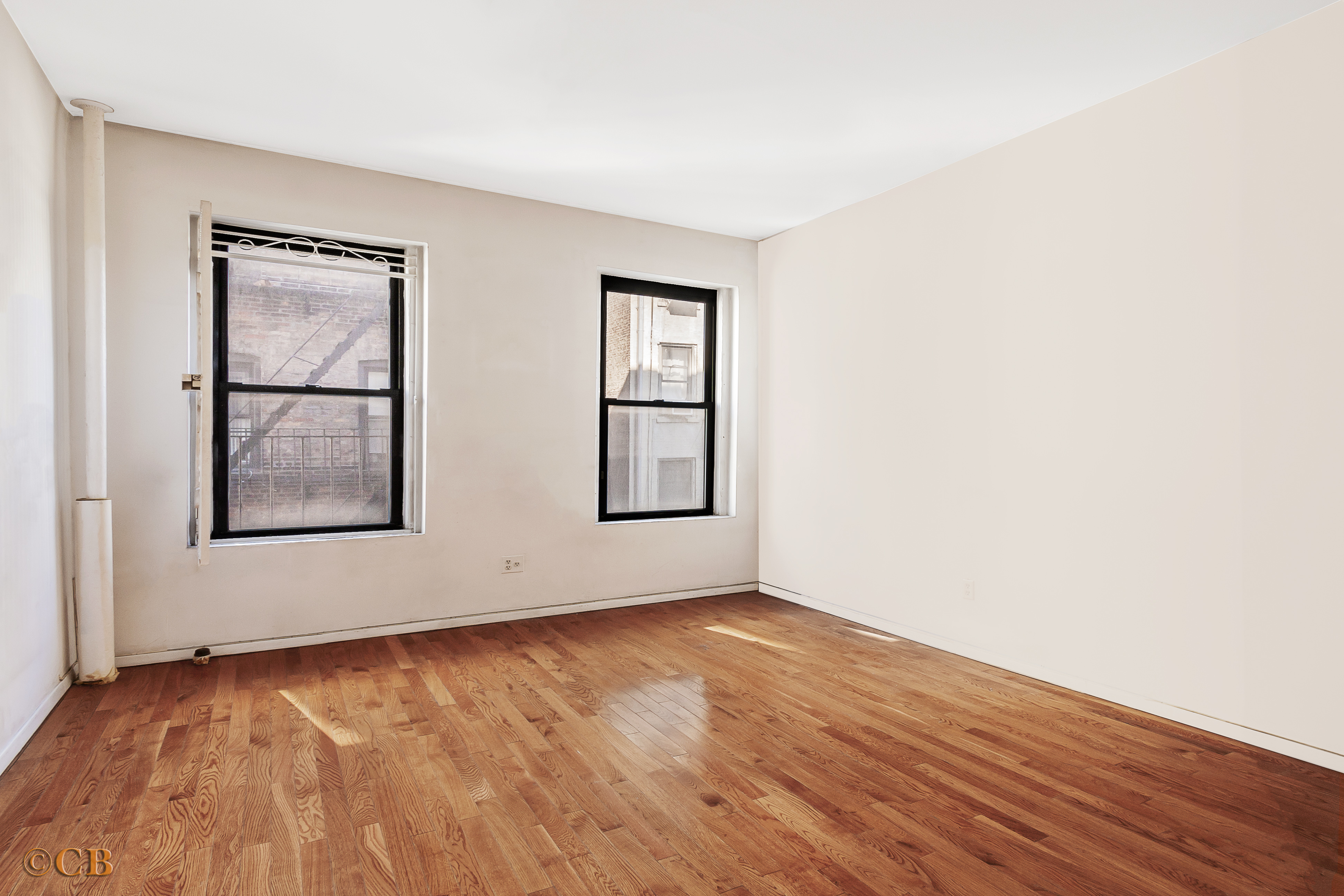 131 Thompson Street, Unit 4C Manhattan, NY 10012 - Photo 2 of 9 an empty room with wooden floor and windows