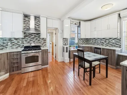 a kitchen with a stove a sink and wooden floor