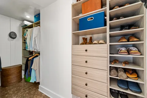 a view of walk in closet with clothes and shoes