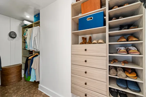 a view of walk in closet with clothes and shoes