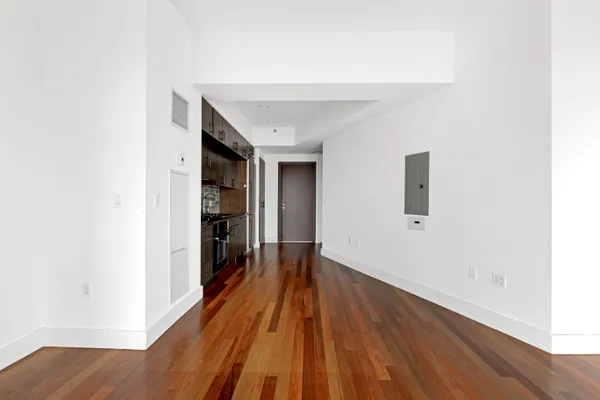 a view of a hallway with wooden floor and a bathroom