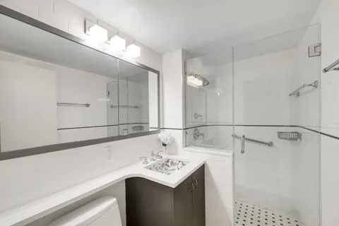 a bathroom with a sink vanity and a shower