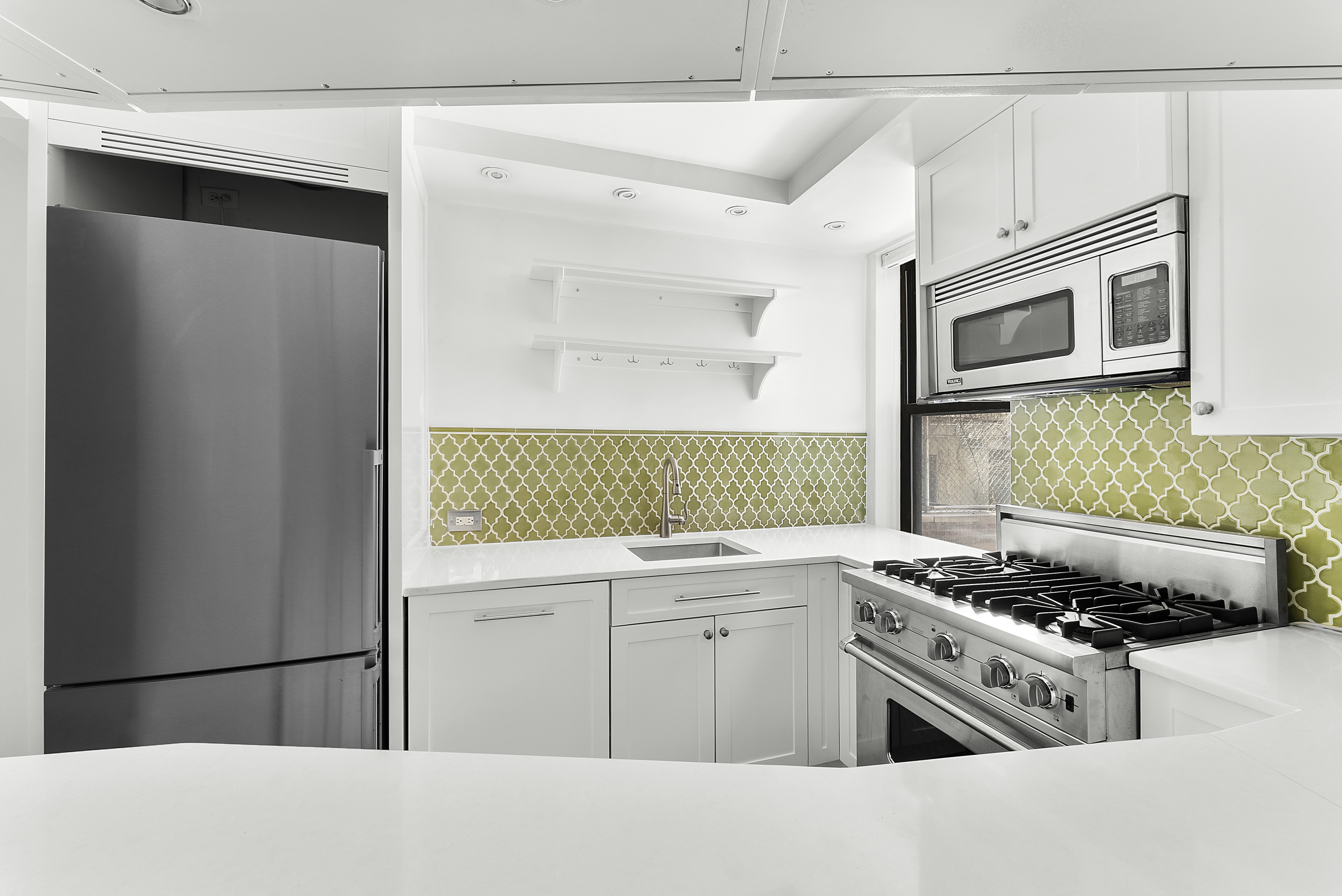 100 Bank Street, Unit 1H Manhattan, NY 10014 - Photo 4 of 10 a kitchen with stainless steel appliances granite countertop a stove and a microwave