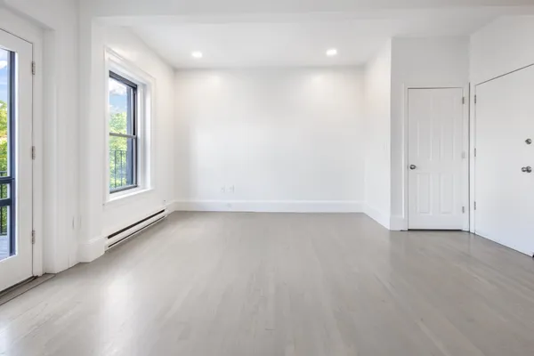 an empty room with wooden floor and windows