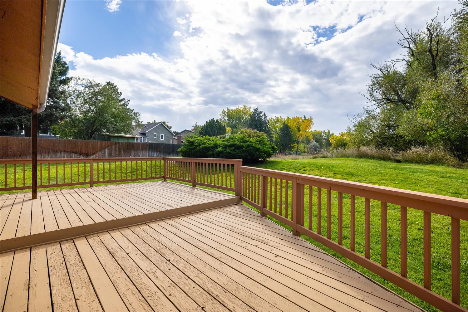 a view of deck with wooden floor and fence next to a yard