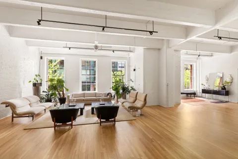 a living room with furniture large window and wooden floor
