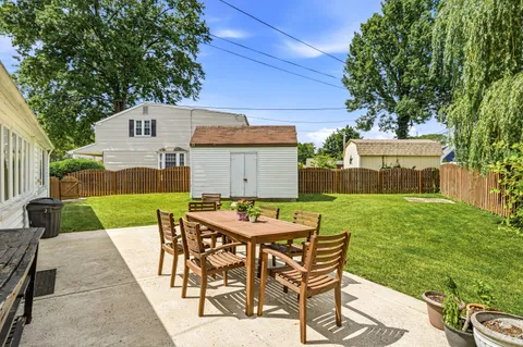 a patio with a table and chairs and potted plants