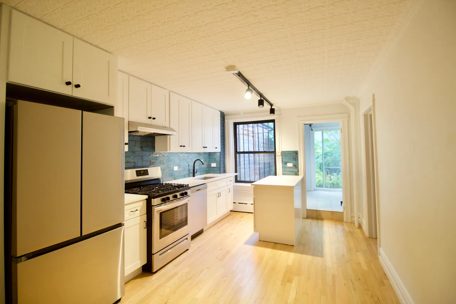 a kitchen with granite countertop a refrigerator a stove top oven and white cabinets with wooden floor