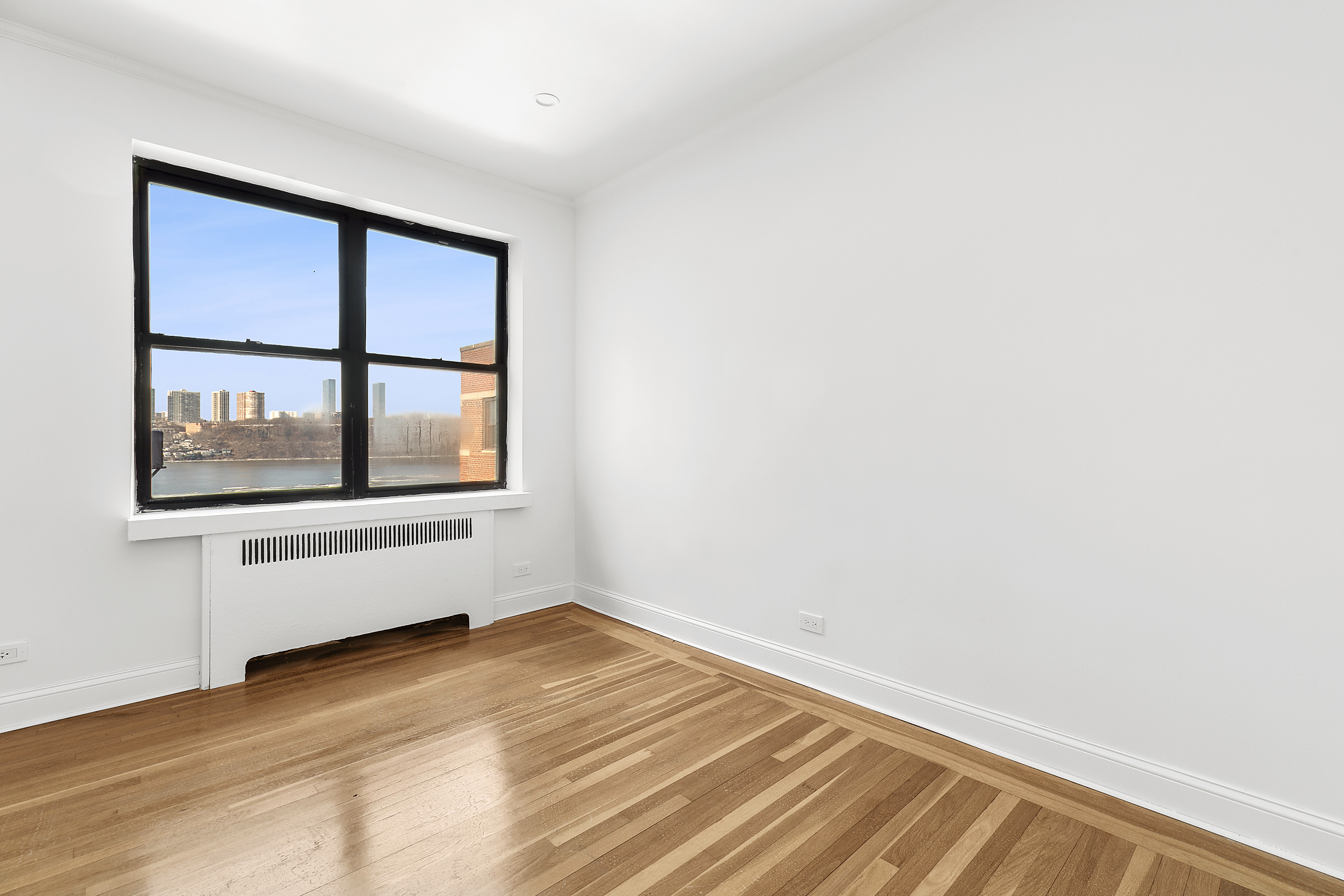 159-34 Riverside Drive West, Unit 7L90 Manhattan, NY 10032 - Photo 4 of 22 a view of empty room with wooden floor and fan