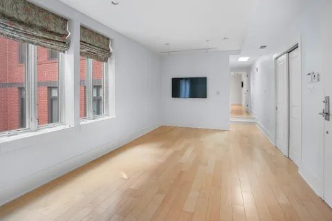 a view of empty room with wooden floor and fan