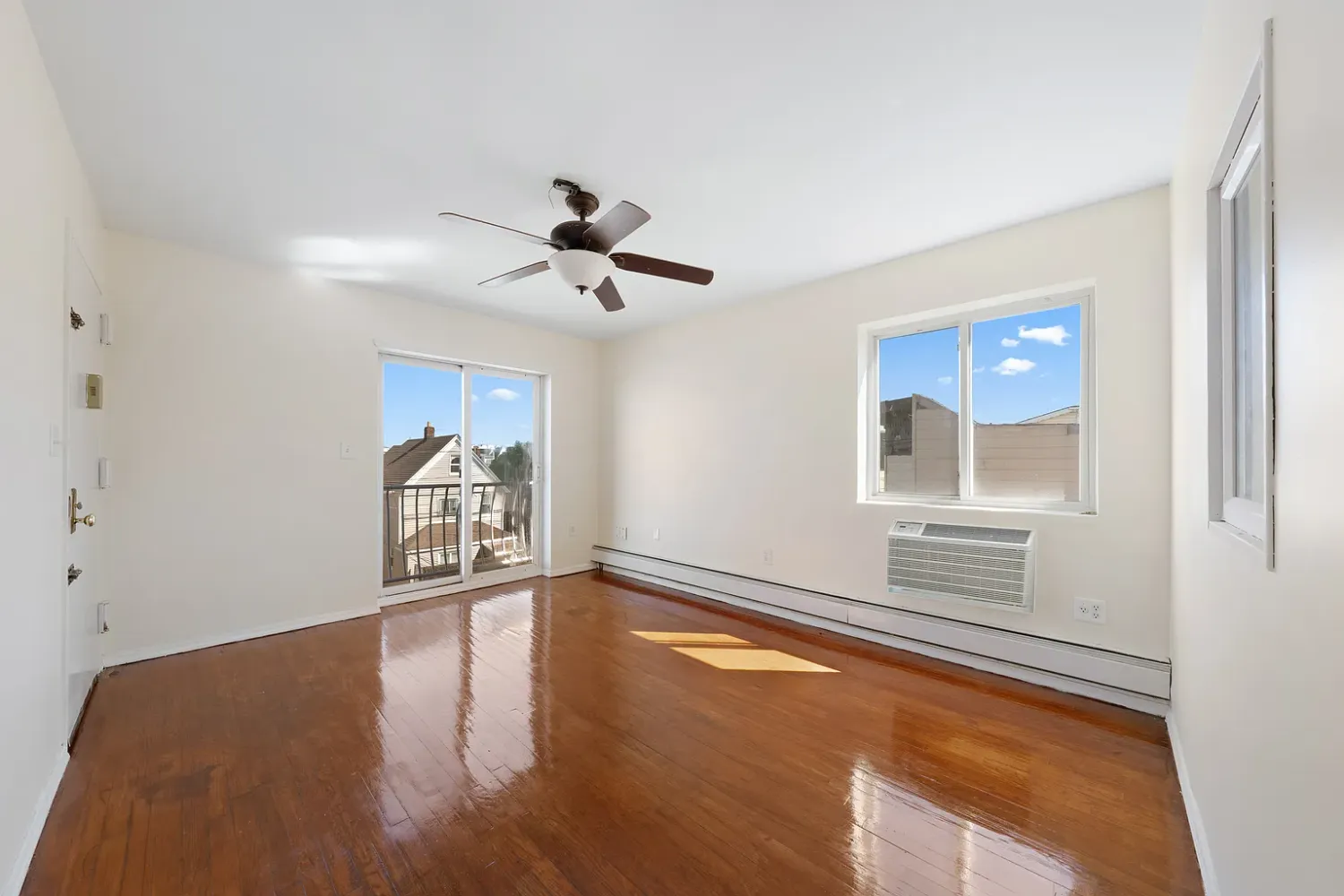 a view of an empty room with a window and wooden floor