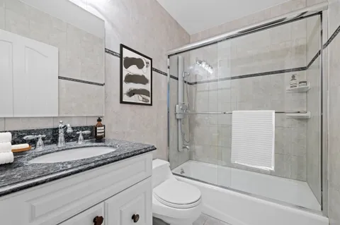 a bathroom with a granite countertop sink mirror toilet and bathtub