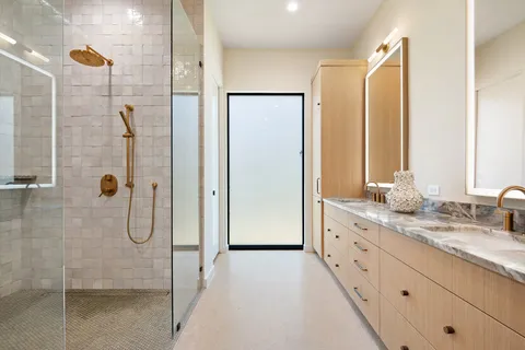 a bathroom with a granite countertop sink two mirror and shower