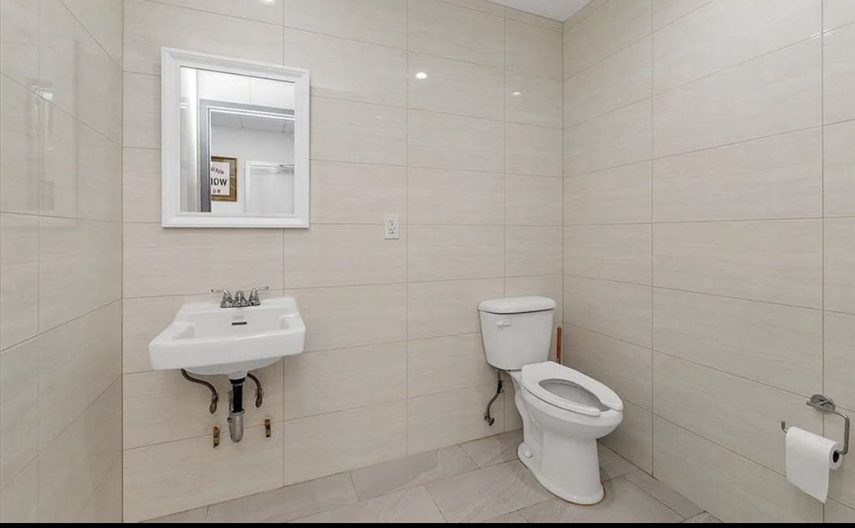 142-38 37th Avenue, Unit 2G Flushing, NY 11354 - Photo 6 of 8 a bathroom with a toilet sink and mirror