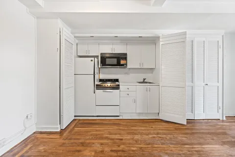 a view of kitchen with granite countertop cabinets and refrigerator