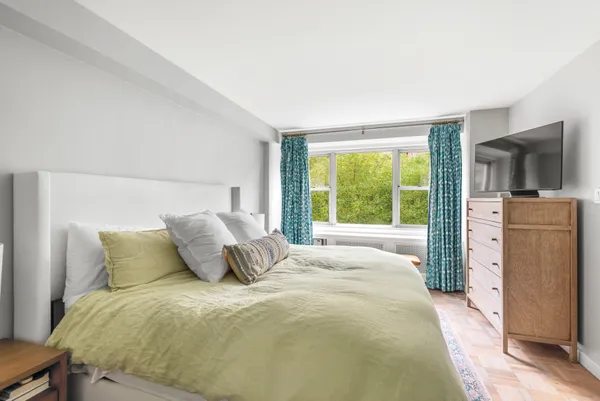 a bedroom with a bed flat screen tv and large window