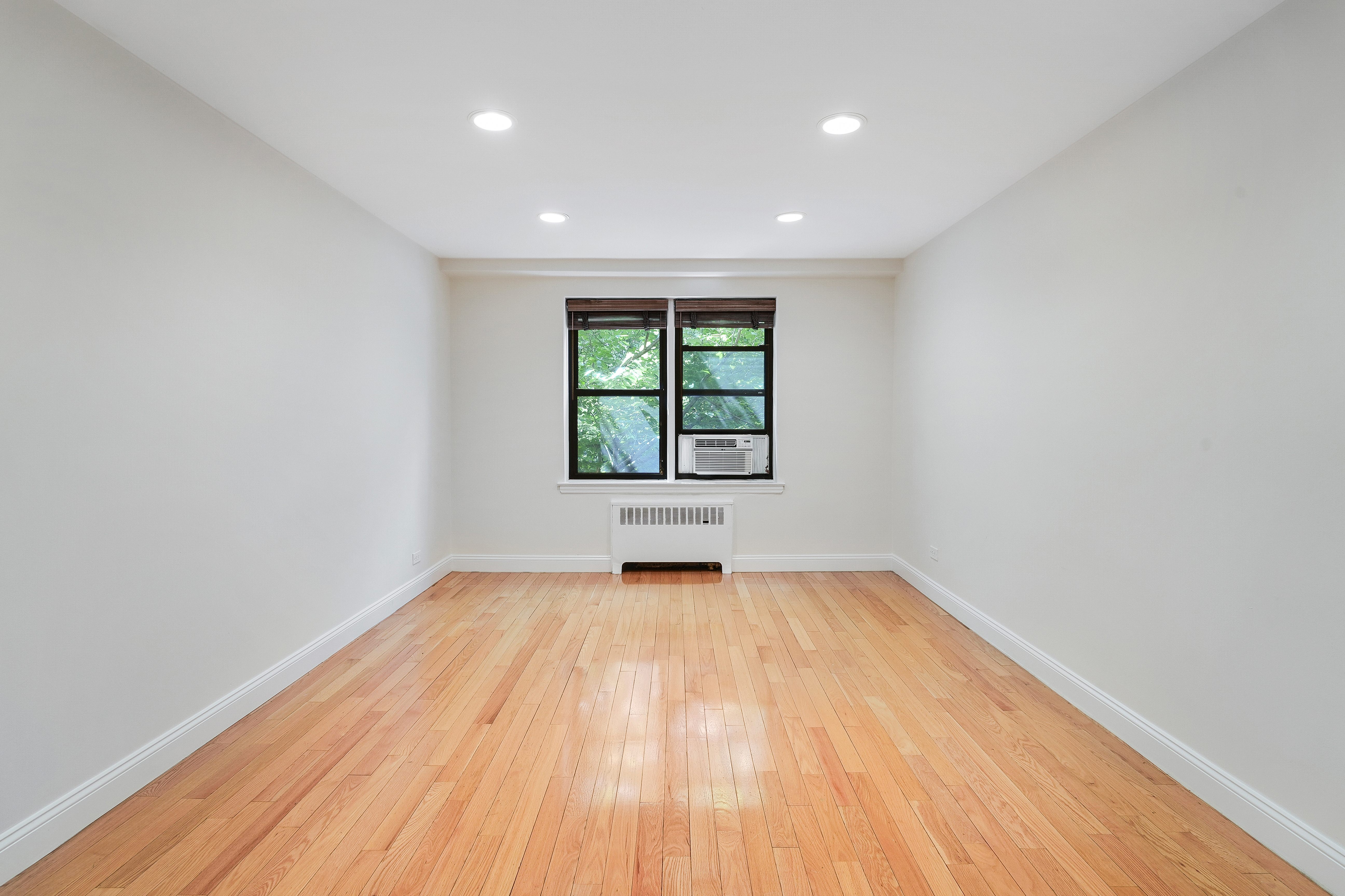 3840 Greystone Avenue, Unit 1K Bronx, NY 10463 - Photo 3 of 13 an empty room with wooden floor and windows
