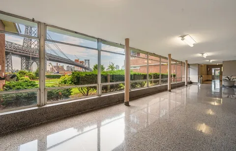 a view of an empty room with wooden floor and a large window