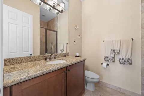 a bathroom with a granite countertop sink a toilet and a mirror
