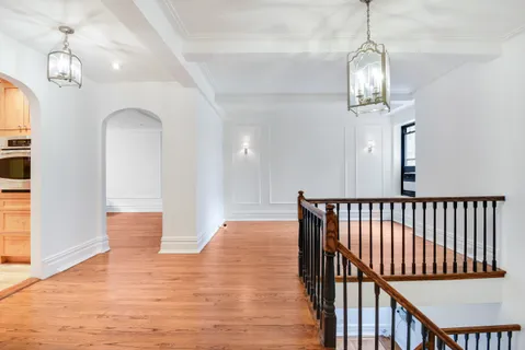 a view of a hallway with wooden floor and chandelier