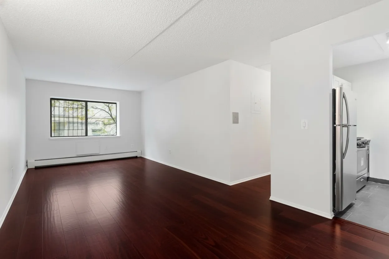 a view of an empty room with wooden floor and a window