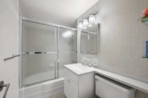 a bathroom with a shower sink vanity and mirror