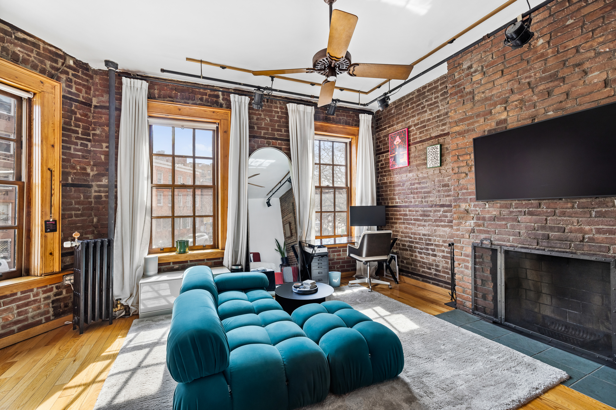 31 8th Avenue, Unit 1 Manhattan, NY 10014 - Photo 1 of 10 a living room with furniture a fireplace and a flat screen tv