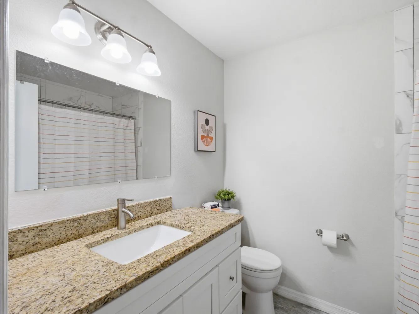 a bathroom with a granite countertop sink mirror vanity and toilet