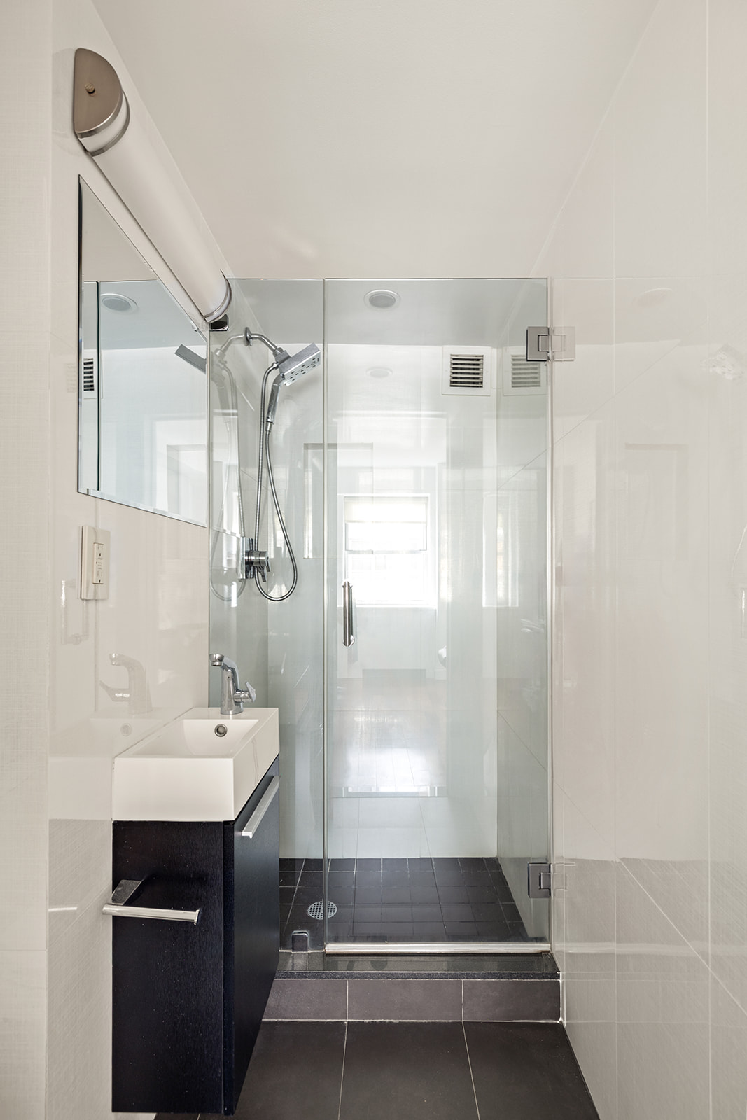 330 East 49th Street, Unit 12E Manhattan, NY 10017 - Photo 13 of 16 a bathroom with a shower sink vanity and mirror