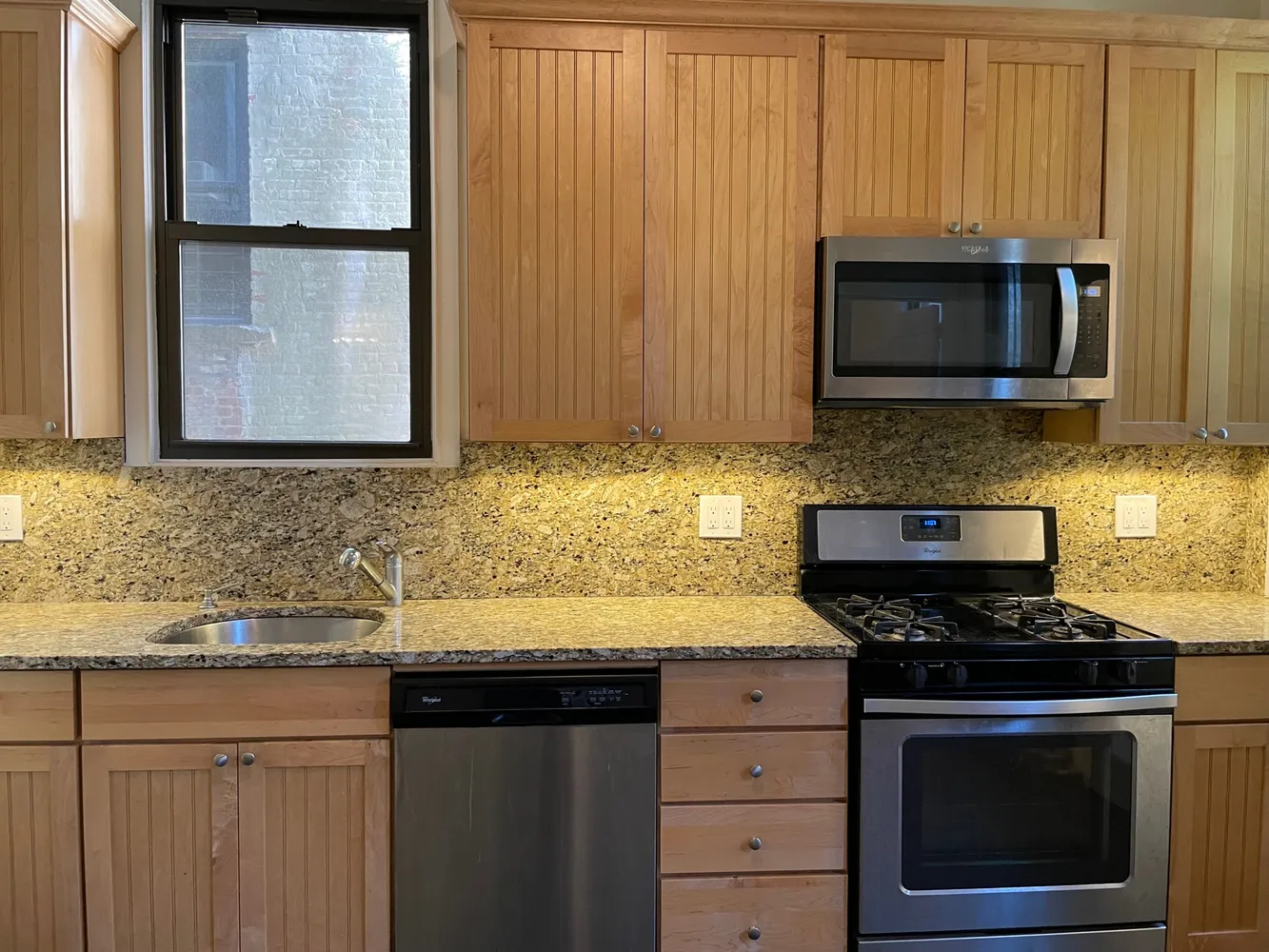 a kitchen with granite countertop a sink stove and microwave