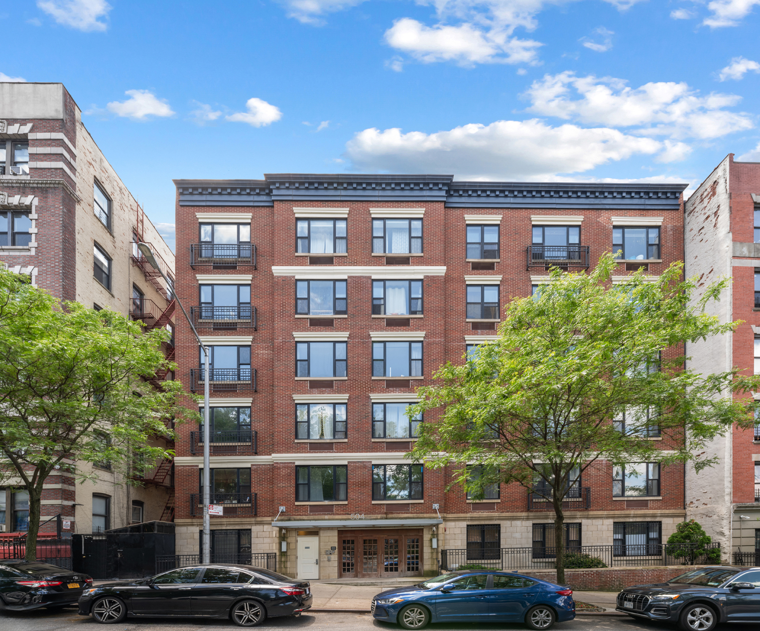 504 West 136th Street, Unit 6A Manhattan, NY 10031 - Photo 9 of 10 a front view of a building with lot of cars and trees