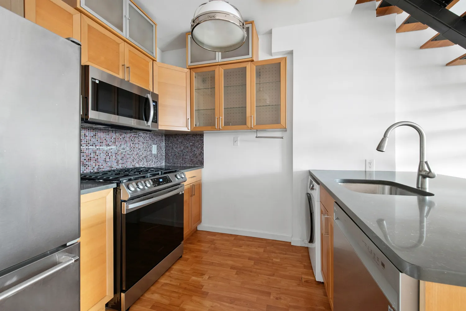a kitchen with stainless steel appliances granite countertop a sink and a stove top oven with wooden floor