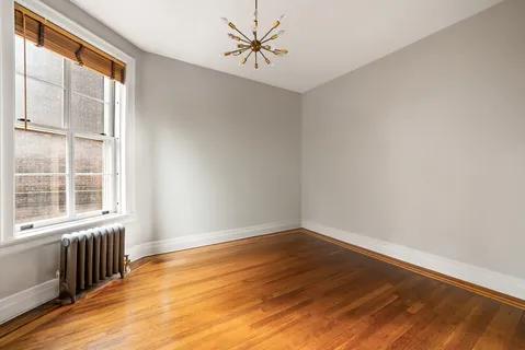 a view of an empty room with a window and wooden floor