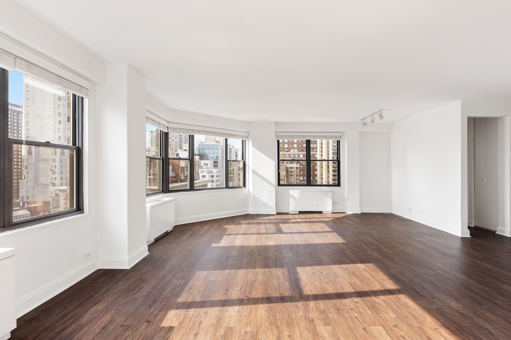 120 East 90th Street, Unit 16E Manhattan, NY 10128 - Photo 8 of 15 a view of an empty room with wooden floor and a window