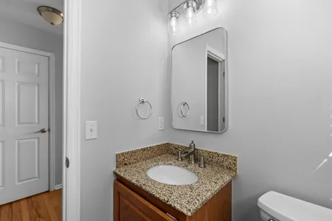 a bathroom with a granite countertop sink toilet and mirror
