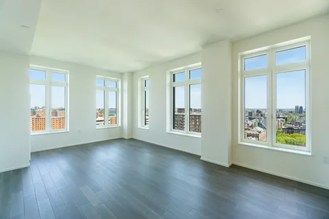 a view of an empty room with a window and wooden floor