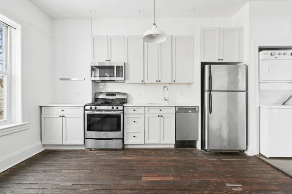 a kitchen with stainless steel appliances a refrigerator stove and white cabinets