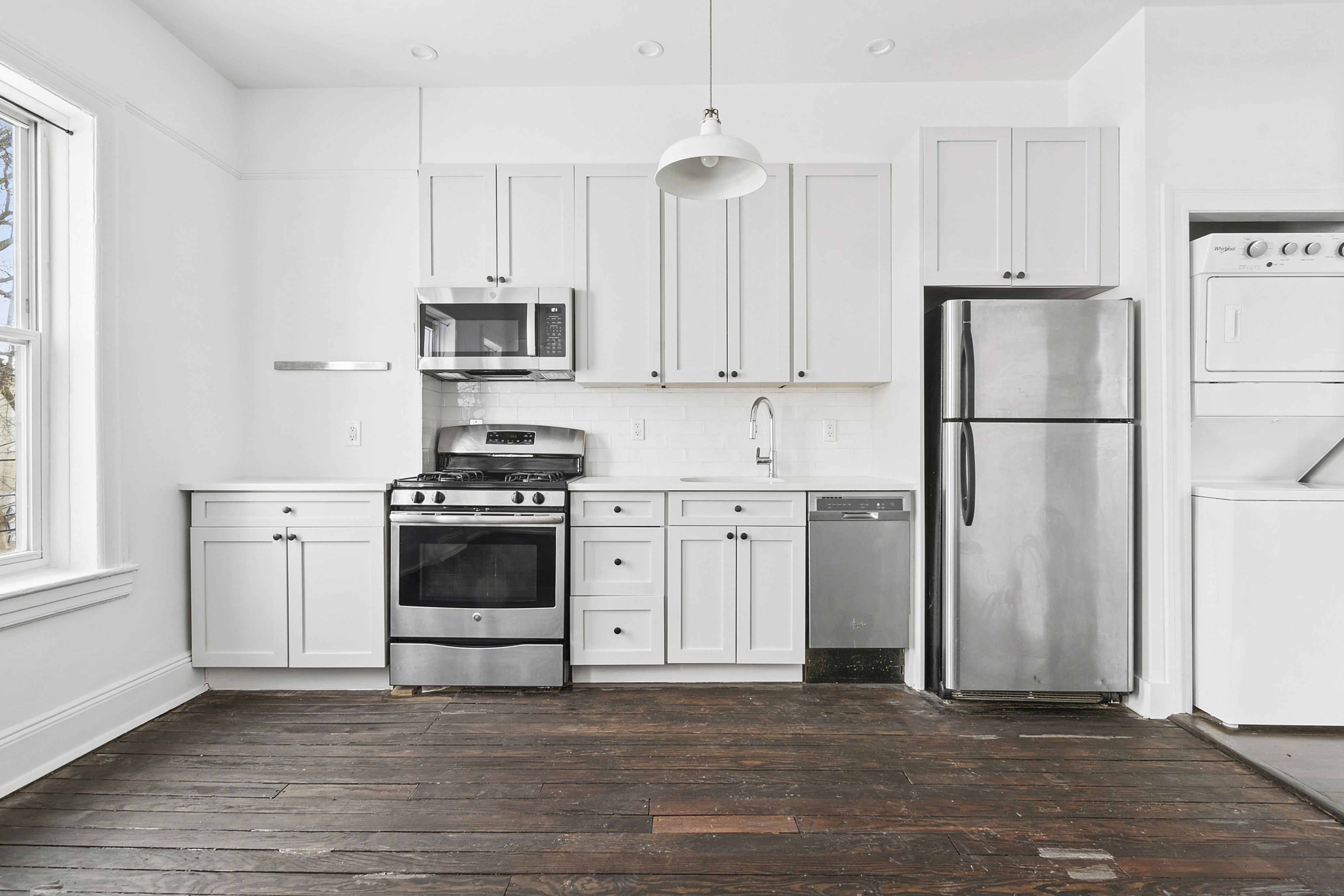 239 East 23rd Street, Unit 2 Brooklyn, NY 11226 - Photo 2 of 8 a kitchen with stainless steel appliances a refrigerator stove and white cabinets