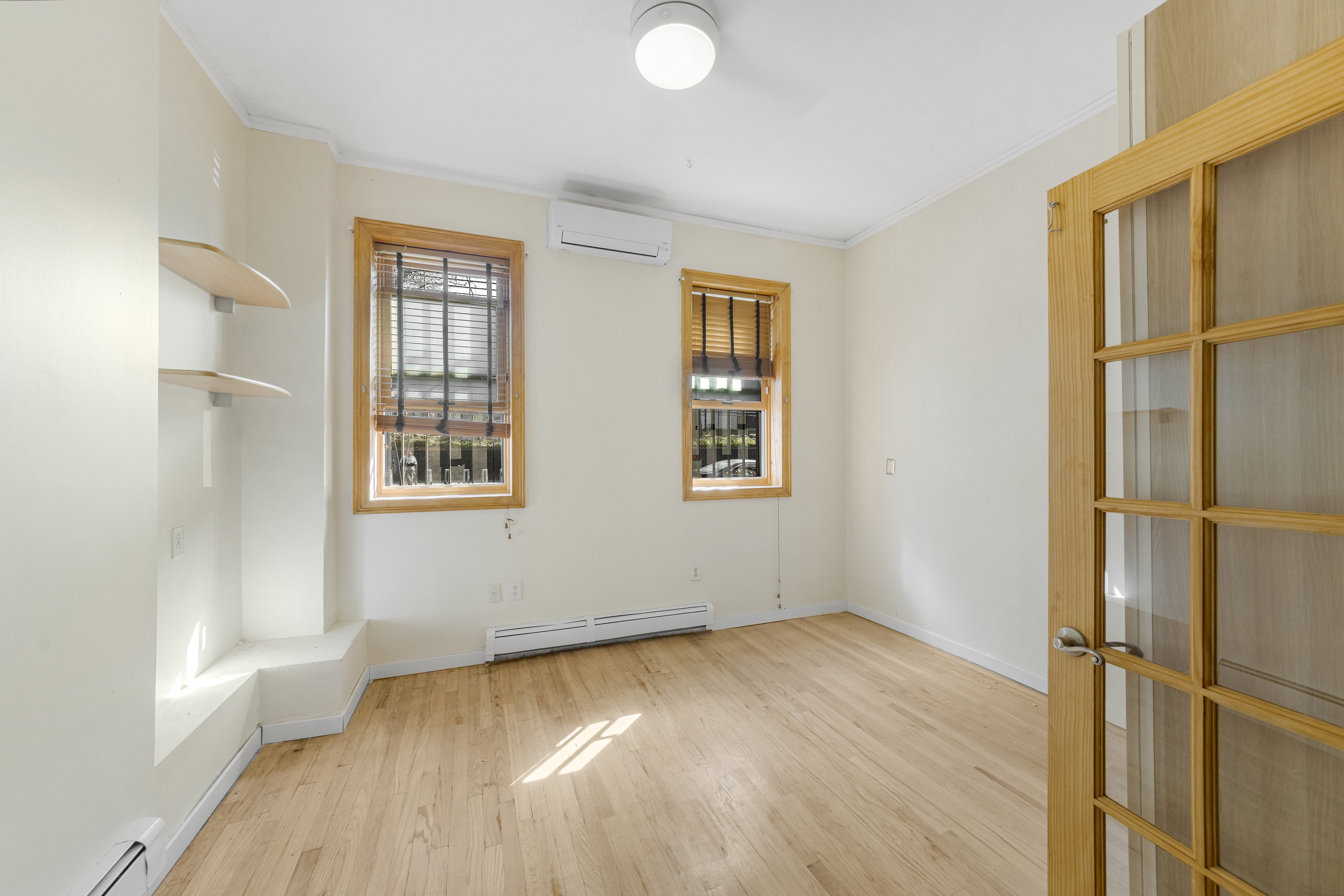 1061 Fulton Street, Unit 1 Brooklyn, NY 11238 - Photo 5 of 13 an empty room with wooden floor and windows