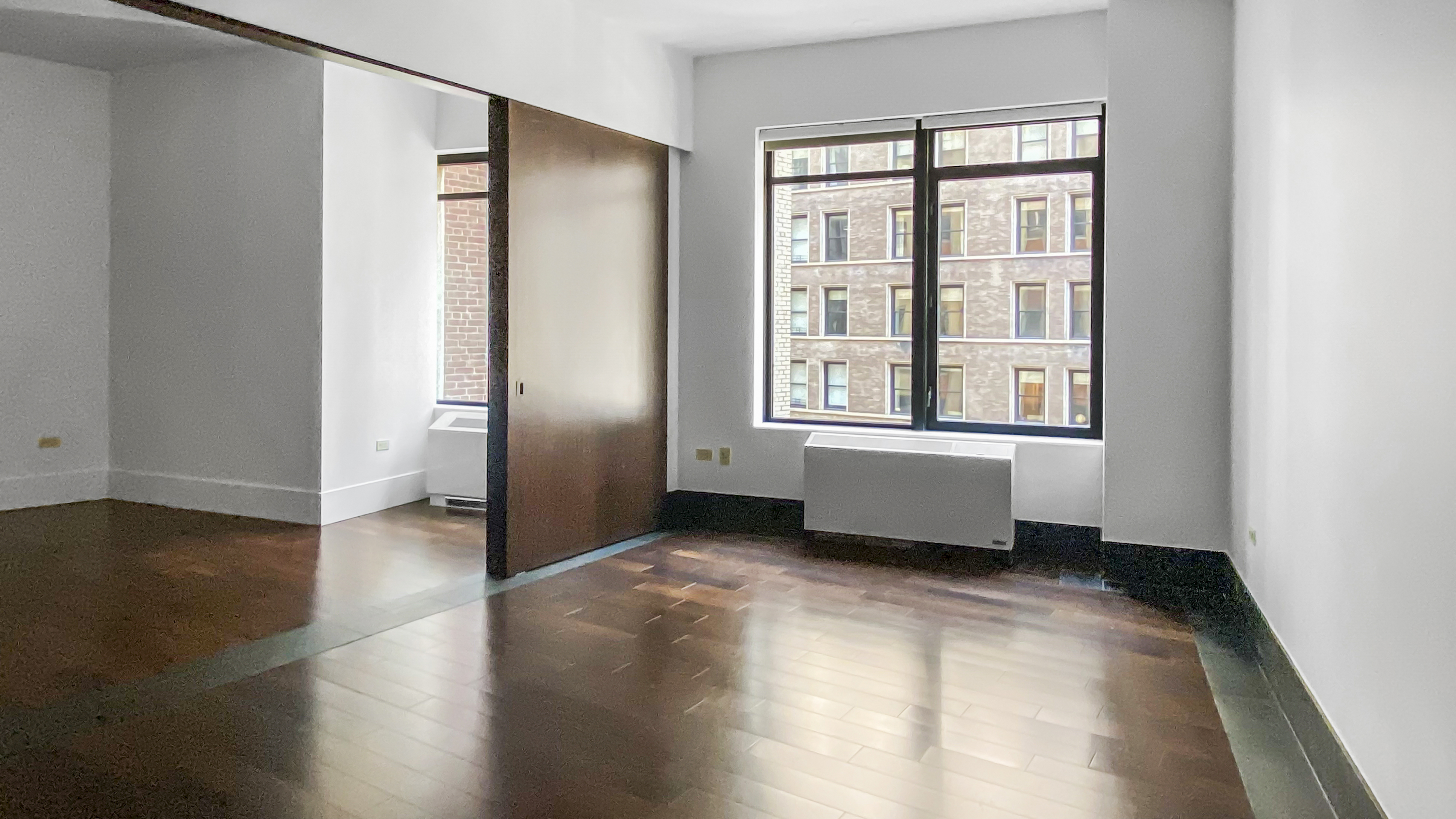 40 Broad Street, Unit 16E Manhattan, NY 10004 - Photo 2 of 16 an empty room with wooden floor and windows