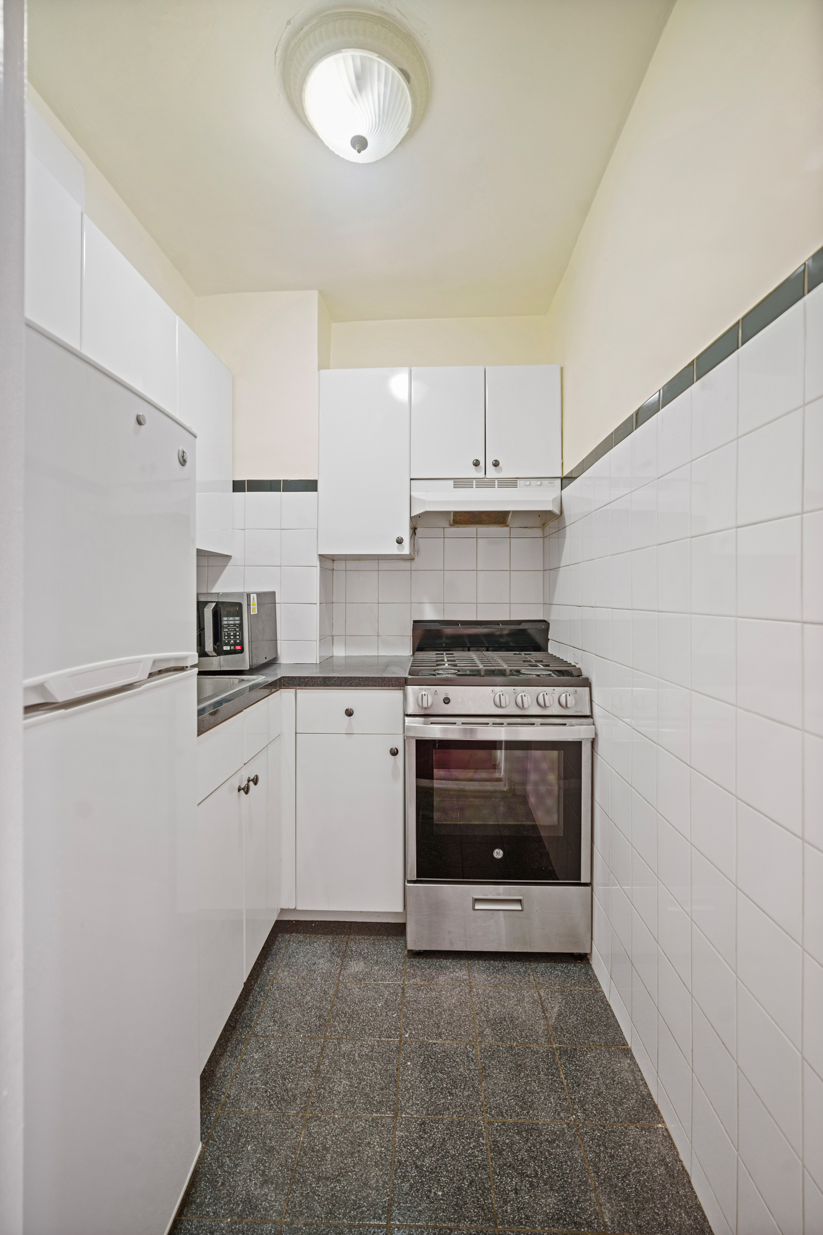 210 East 63rd Street, Unit 8C Manhattan, NY 10065 - Photo 6 of 12 a kitchen with a stove and a refrigerator