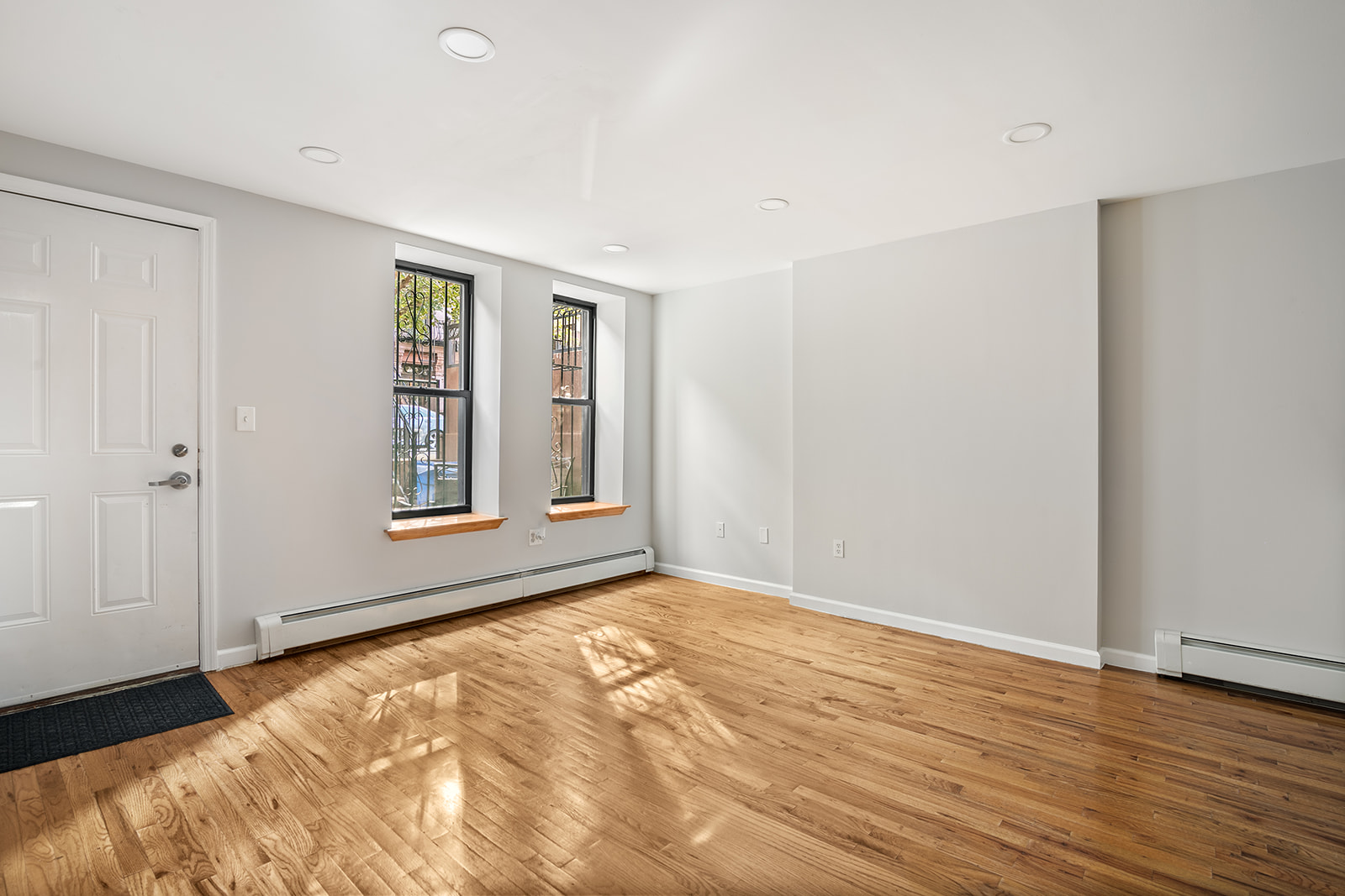 265 West 136th Street Manhattan, NY 10030 - Photo 8 of 14 a view of an empty room with wooden floor and a window