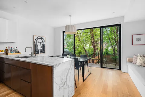 a view of a kitchen with kitchen island a large window cabinets a sink and stainless steel appliances